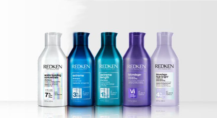 A row of 8 different colored bottles of Redken shampoos for all hair types against a white background.