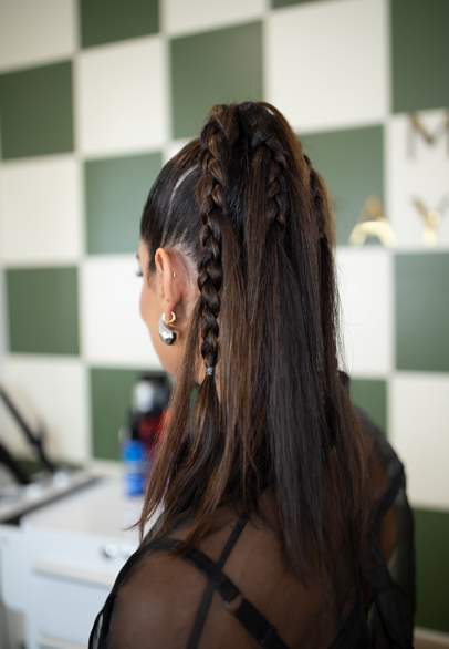 Woman with brunette hair styled in braids pulled back into a half-up ponytail.